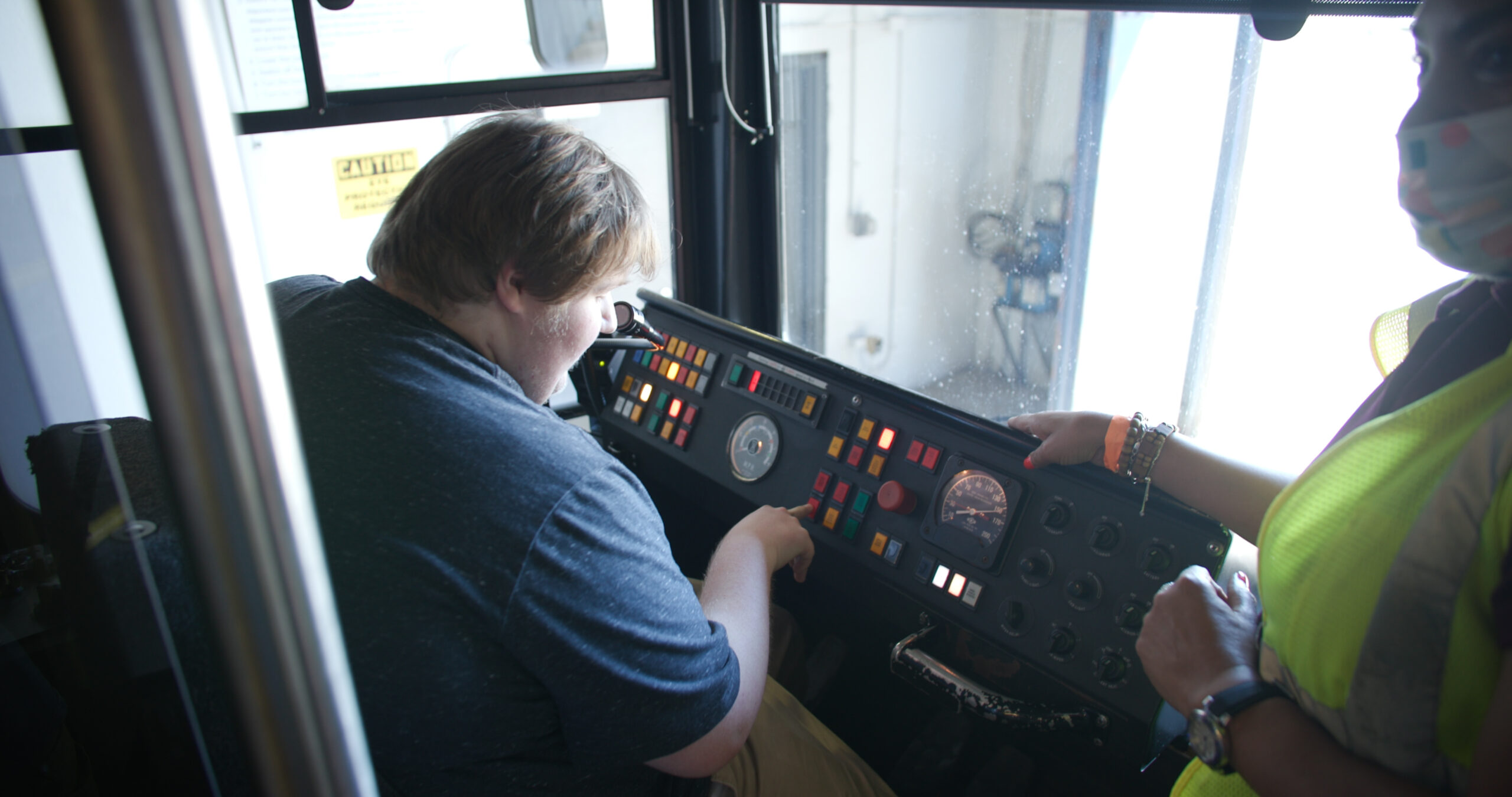 A student presses buttons at the control panel of a Metro train